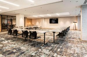 une salle de conférence avec des tables, des chaises et une télévision dans l'établissement Canvas Moncton, Tapestry Collection By Hilton, à Moncton