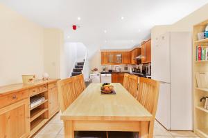 uma cozinha com uma mesa de madeira e um frigorífico branco em Charming 4 bed town house with roof terrace em Londres