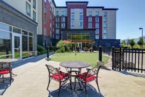 een patio met een tafel en stoelen en een tennisbaan bij Homewood Suites by Hilton Toronto-Ajax in Ajax