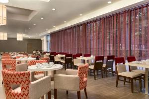 uma sala de jantar com mesas, cadeiras e cortinas em DoubleTree by Hilton Hotel Toronto Airport West em Mississauga