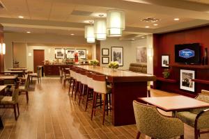 a restaurant with a bar and tables and chairs at Hampton Inn by Hilton Brampton - Toronto in Brampton