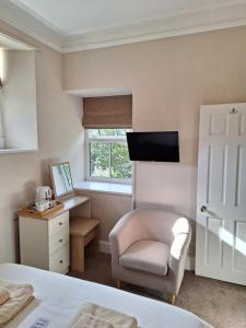 a bedroom with a bed and a chair and a mirror at Ferndale Lodge in Ambleside