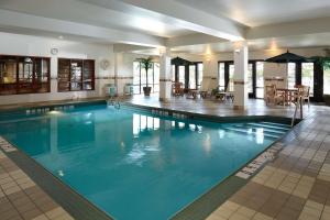 a large swimming pool in a hotel with tables and chairs at Hampton Inn & Suites Montreal-Dorval in Dorval