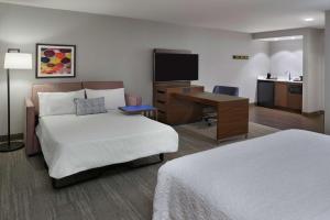 a hotel room with a bed and a desk with a computer at Hampton Inn & Suites Montreal-Dorval in Dorval +21 photos