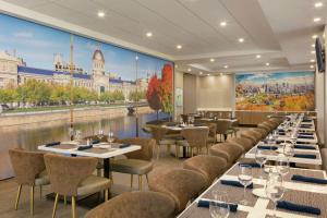 un restaurante con mesas y sillas y un mural de una ciudad en Embassy Suites By Hilton Montreal Airport, en Pointe-Claire