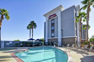 a hotel with a swimming pool and palm trees at Hampton Inn & Suites Yuma in Yuma