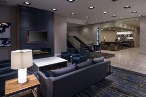 a lobby with blue chairs and a tv and stairs at Doubletree by Hilton London in London