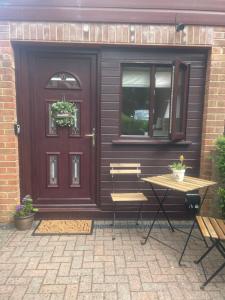 una puerta marrón con 2 sillas y una mesa en The Cotswold Nook, en Dursley