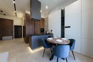 a kitchen and dining room with a wooden table and blue chairs at Luxury Apartments BUDAPEST in Uzhhorod