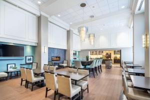 a dining room with tables and chairs and a fireplace at Hampton Inn & Suites by Hilton Toronto Airport in Mississauga