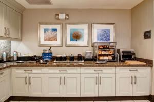 Homewood Suites by Hilton Toronto-Markham في ماركهام: مطبخ بدولاب بيضاء وقمة كونتر