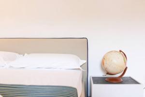 ein weißes Schlafzimmer mit einem Bett und einer Uhr auf einem Nachttisch in der Unterkunft H.Verde Sorrento Apartment in Sant'Agnello
