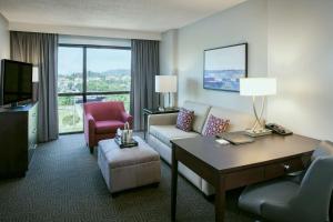 um quarto de hotel com um sofá, uma mesa e uma televisão em Hilton Suites Brentwood em Brentwood