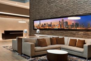 Embassy Suites by Hilton Chicago Lombard في لومبارد: غرفة معيشة مع أريكة وتلفزيون بشاشة مسطحة