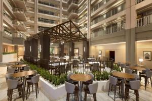 a restaurant with tables and chairs in a building at Embassy Suites by Hilton Chicago Lombard in Lombard