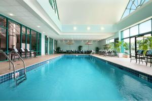 uma piscina num hotel com cadeiras e mesas em Embassy Suites by Hilton Chicago Lombard em Lombard