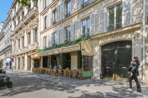 a woman walking down a street in front of a building at La Maison Kléber - Luxury apartments, Eiffel Tower - Champs-Elysées in Paris
