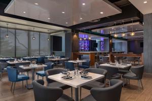 un restaurante con mesas blancas y sillas azules en Embassy Suites By Hilton Toronto Airport, en Toronto