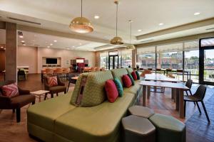 ein Wohnzimmer mit einem Sofa, Tischen und Fenstern in der Unterkunft Home2 Suites By Hilton Jekyll Island in Jekyll Island