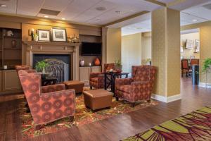 a lobby with a fireplace and chairs and a table at Hampton Inn & Suites Charlotte Arrowood Rd in Charlotte