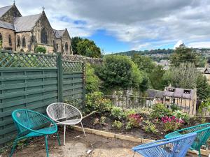 two blue chairs sitting in a garden next to a fence at The Bell Chime, renovated 3 bedroom cottage in Matlock in Matlock Bank