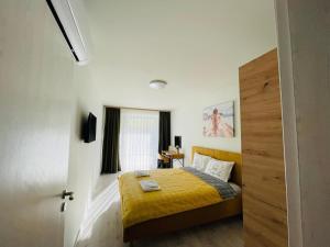 1 dormitorio con 1 cama con manta amarilla en Apartment Perla - АТЕА Complex, en Kavarna