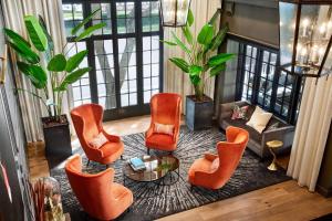 a living room with orange chairs and a table at The Terrace Hotel Lakeland, Tapestry Collection by Hilton in Lakeland