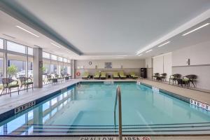 - une piscine dans un hôtel avec des chaises et des tables dans l'établissement Hilton Garden Inn Toronto/Brampton West, Ontario, Canada, à Brampton
