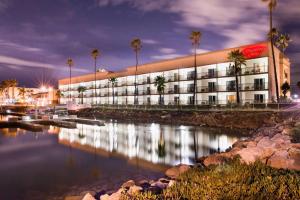 a building with palm trees in front of a body of water at Hampton Inn Channel Islands Harbor in Oxnard