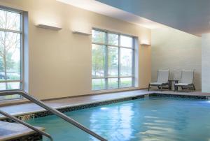 uma piscina com duas cadeiras e uma mesa em Homewood Suites by Hilton Needham Boston em Needham