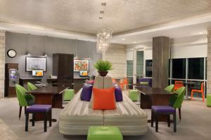 een kamer met tafels en stoelen en een bed met kleurrijke kussens bij Home2 Suites by Hilton Austin North/Near the Domain, TX in Austin