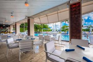 un restaurante con mesas y sillas y una piscina en Hilton Bentley Miami South Beach, en Miami Beach