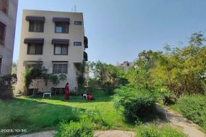 a group of people sitting in a yard next to a building at 3 Luxury BedRoom Set OSHO Villa Jaipur Airport in Jaipur