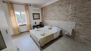 a bedroom with a bed and a brick wall at Hera Tropea Rooms in Tropea