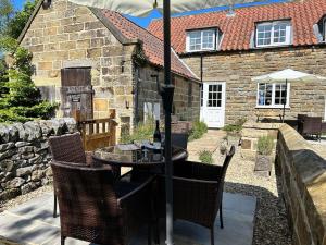 a table with chairs and an umbrella in front of a house at Smugglers Rock Cottages in Ravenscar