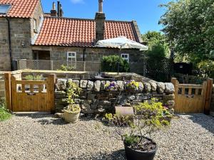 a garden with a stone wall and some plants at Smugglers Rock Cottages in Ravenscar