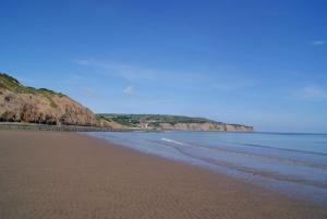 a sandy beach with the ocean and cliffs in the background at Smugglers Rock Cottages in Ravenscar
