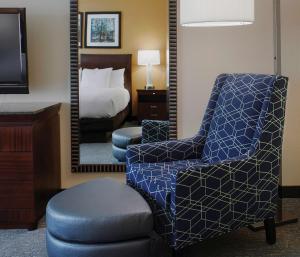 een slaapkamer met een bed, een stoel en een spiegel bij DoubleTree Suites by Hilton Bentonville in Bentonville