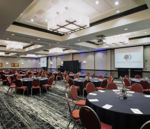 una sala de conferencias con mesas, sillas y una pantalla en DoubleTree Suites by Hilton Bentonville en Bentonville