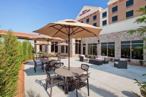 un patio con mesas, sillas y una sombrilla en Hilton Garden Inn Springfield, MO en Springfield