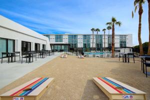 un edificio con piscina, mesas y palmeras en Doubletree By Hilton Palmdale, Ca en Palmdale