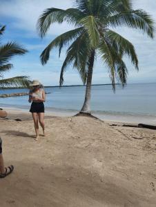 a woman walking on the beach with a palm tree at PLAYABRISAMAR in San Antero