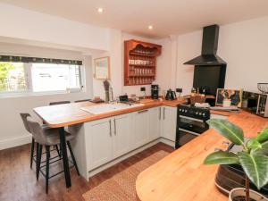 a kitchen with white cabinets and a wooden counter top at Goosedale Cottage in Scarborough