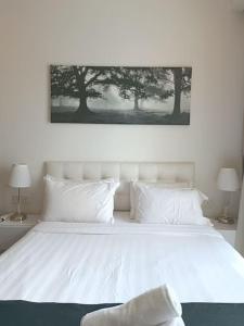 Una cama blanca con almohadas blancas y una foto encima. en RM219 Bukit Bintang Balcony Studio Infinty Pool, en Kuala Lumpur