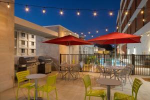 a patio with tables and chairs and red umbrellas at Home2 Suites by Hilton Charlotte Airport in Charlotte