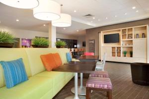 uma sala de espera com um sofá, uma mesa e cadeiras em Home2 Suites by Hilton Charlotte Airport em Charlotte