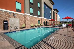 a swimming pool with chairs and a building at Hampton Inn Fresno Airport in Fresno