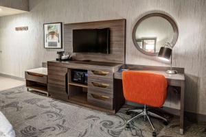 Habitación de hotel con escritorio, TV y espejo. en Hampton Inn Fresno Airport en Fresno