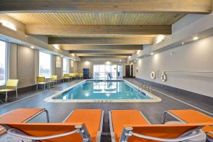 una piscina en una habitación de hotel con sillas naranjas en Home 2 Suites By Hilton Jackson en Jackson