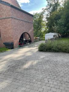 un bâtiment en briques avec une arche en briques devant lui dans l'établissement Le Petit Parc, à Wavre